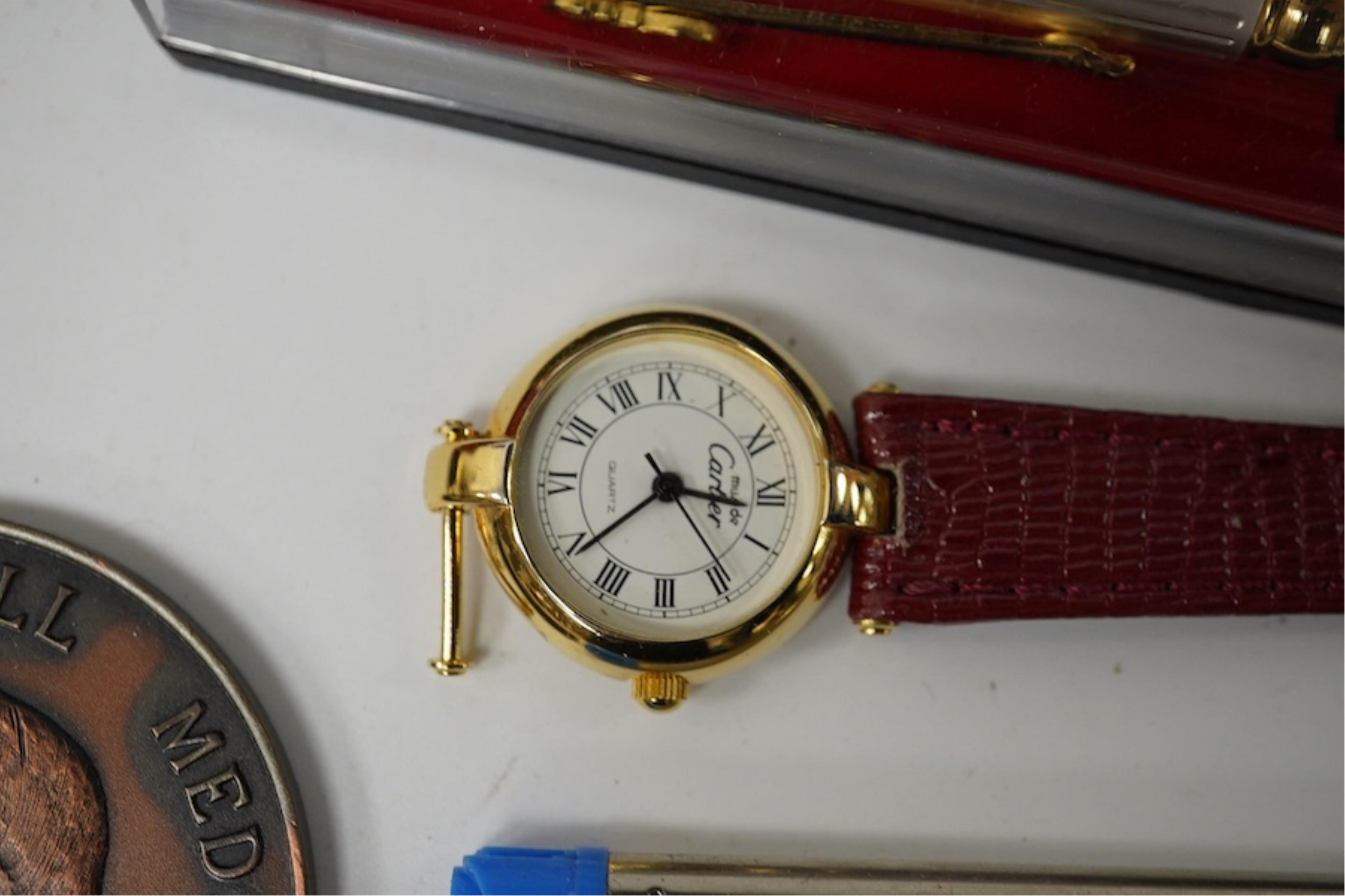 A collection of various pens, a ladies Must de Cartier wrist watch and a H.N. Ansell medal. Condition - varies